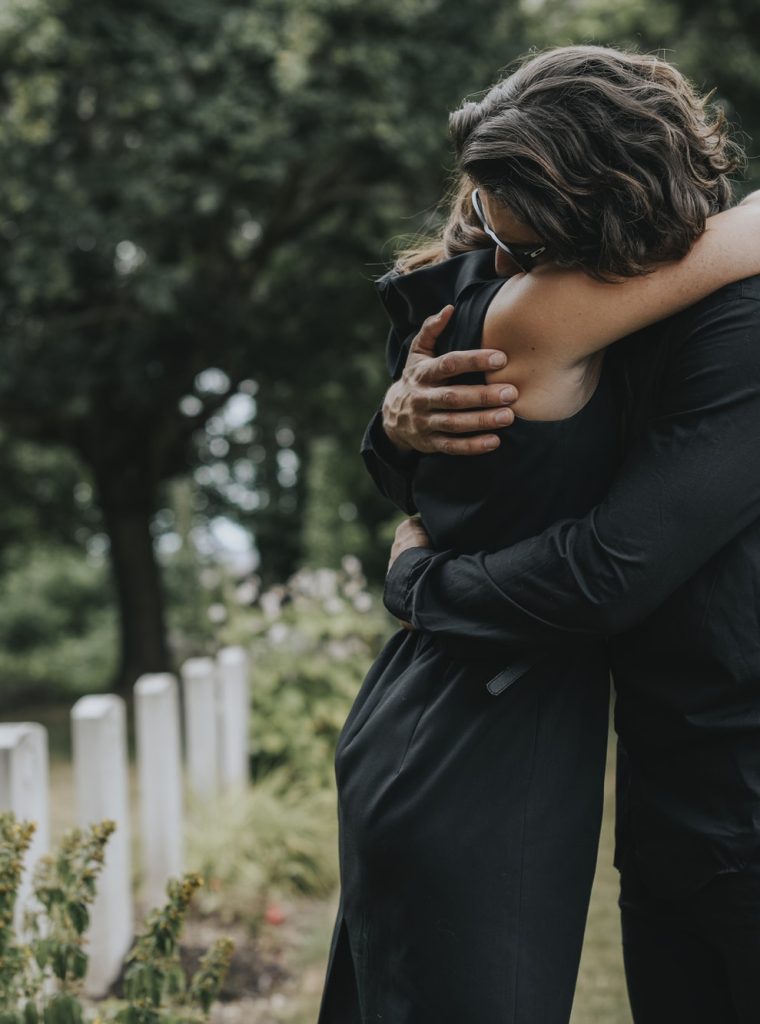 un mari qui tente de réconforter sa femme dans un cimetière