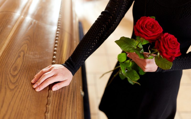 femme avec des roses rouges et un cercueil lors d'un enterrement