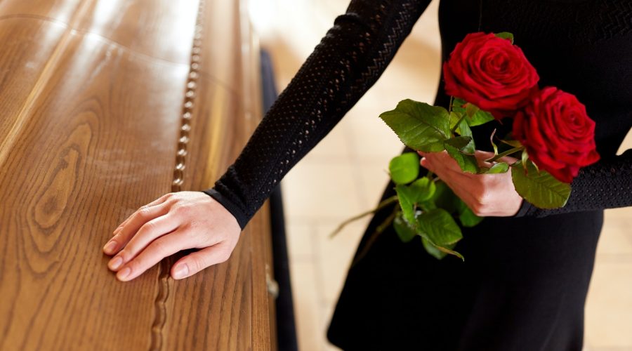 femme avec des roses rouges et un cercueil lors d'un enterrement